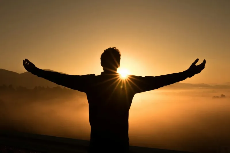 Person with arms wide open at sunrise