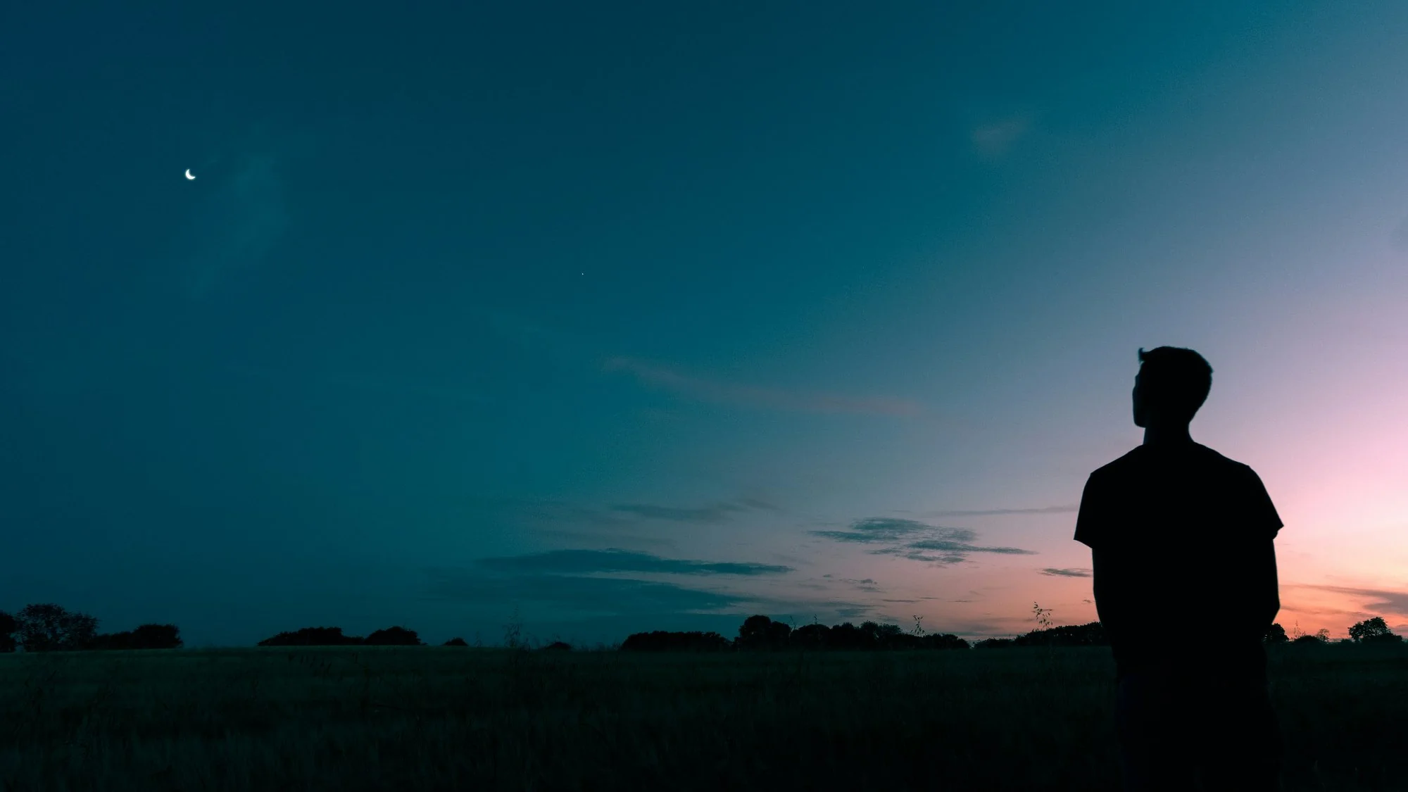 Silhouette of a person standing alone at dusk